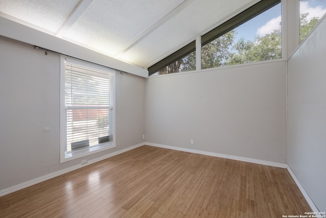 6914 Glen Gate, San Antonio, TX 78239 - spare room featuring healthy amount of natural light, light wood-style floors, lofted ceiling, and a textured ceiling