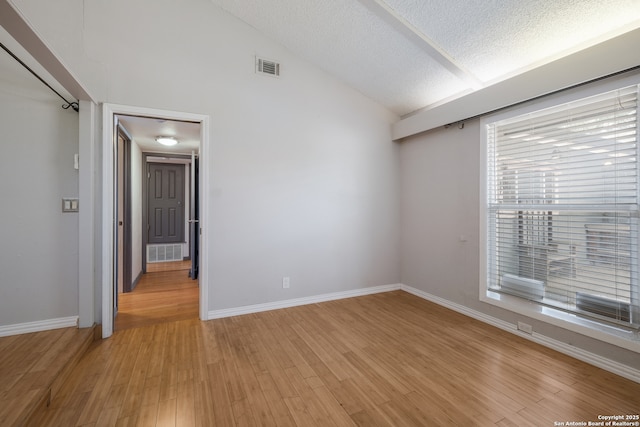 6914 Glen Gate, San Antonio, TX 78239 - spare room featuring a textured ceiling, light wood finished floors, and vaulted ceiling