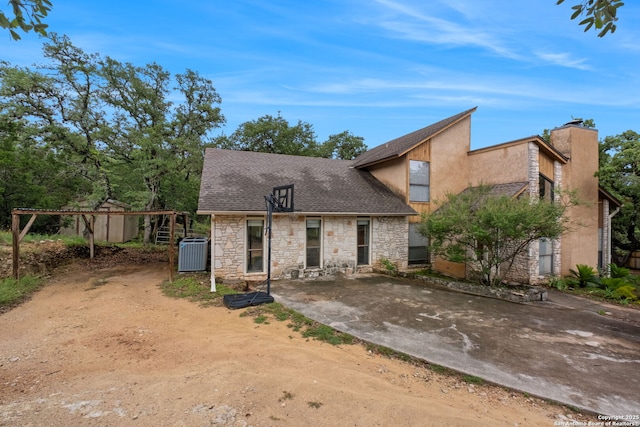 30650 Wildcat Dr, Bulverde, TX 78163 - view of front facade featuring stone siding, a chimney, a shingled roof, and dirt driveway