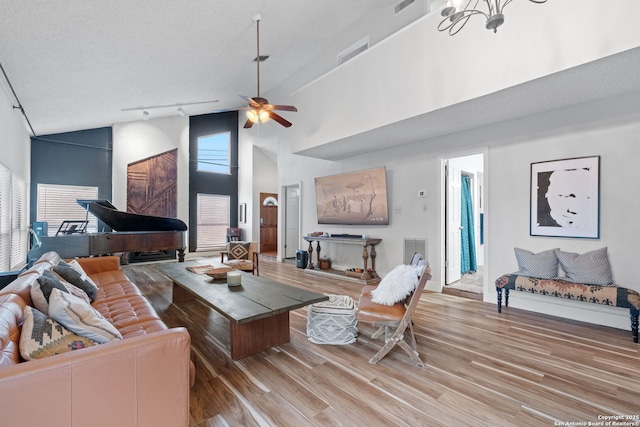 30650 Wildcat Dr, Bulverde, TX 78163 - living room featuring light wood-style floors, high vaulted ceiling, rail lighting, a chandelier, and a ceiling fan