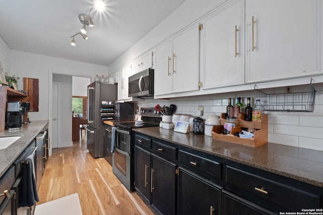 30650 Wildcat Dr, Bulverde, TX 78163 - kitchen with appliances with stainless steel finishes, white cabinetry, dark cabinets, light wood-style floors, and tasteful backsplash