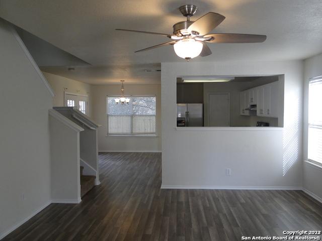 421 Hampton Cv, Boerne, TX 78006 - unfurnished living room featuring a chandelier, dark wood finished floors, ceiling fan, stairway, and healthy amount of natural light