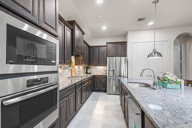 130 Boulder Crk, Boerne, TX 78006 - kitchen with stainless steel appliances, arched walkways, light stone counters, dark brown cabinets, and tasteful backsplash