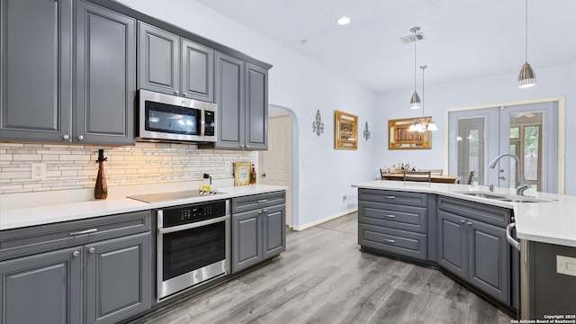 1238 Sugar Land, New Braunfels, TX 78130 - kitchen featuring stainless steel appliances, gray cabinetry, tasteful backsplash, arched walkways, and light countertops