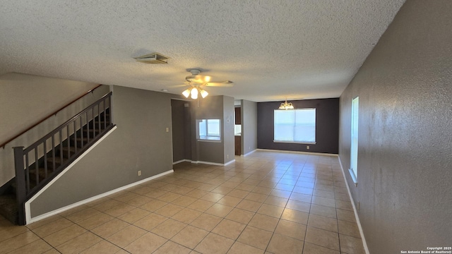 8310 Border Rdg, San Antonio, TX 78240 - empty room with stairway, light tile patterned flooring, a textured ceiling, ceiling fan, and a chandelier