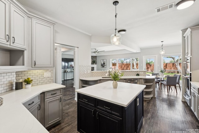 4130 Luckenbach, San Antonio, TX 78251 - kitchen featuring decorative backsplash, a kitchen island, light countertops, dark wood finished floors, and ceiling fan
