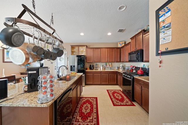 1573 Las Fontanasa, New Braunfels, TX 78132 - kitchen featuring black appliances, a textured ceiling, recessed lighting, brown cabinetry, and light stone countertops