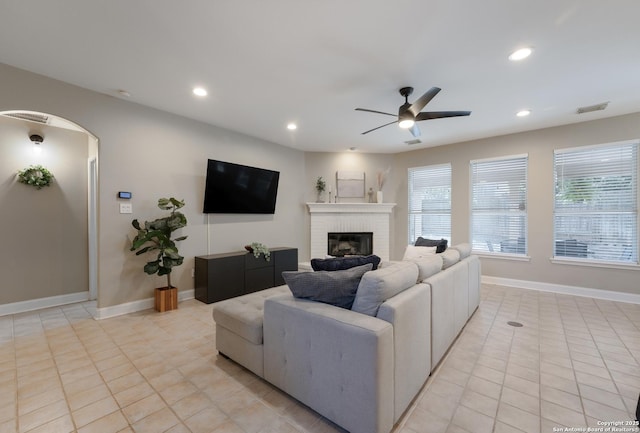 21731 Cliff Vw, San Antonio, TX 78259 - living room featuring a ceiling fan, a brick fireplace, recessed lighting, light tile patterned floors, and arched walkways