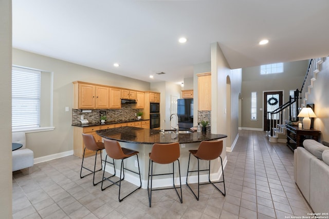 21731 Cliff Vw, San Antonio, TX 78259 - kitchen with backsplash, light brown cabinetry, a kitchen bar, a peninsula, and dark stone counters