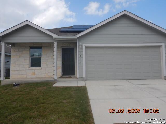 10751 Margarita Loop, Converse, TX 78109 - ranch-style house featuring roof mounted solar panels, driveway, a garage, a front yard, and stone siding