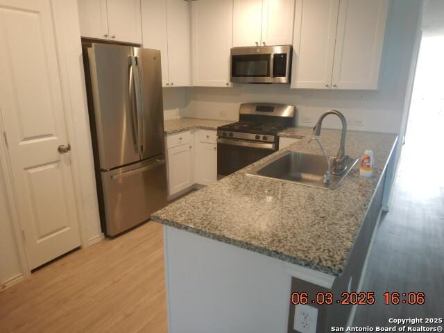 10751 Margarita Loop, Converse, TX 78109 - kitchen with appliances with stainless steel finishes, light wood-style floors, a peninsula, and light stone counters