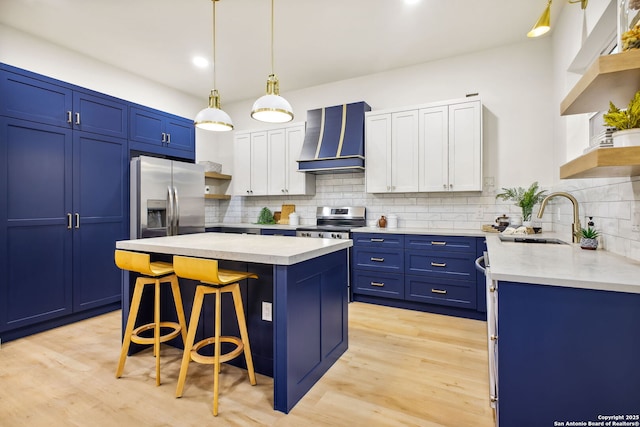 1939 W French Pl, San Antonio, TX 78201 - kitchen with wall chimney exhaust hood, open shelves, appliances with stainless steel finishes, blue cabinetry, and a kitchen island
