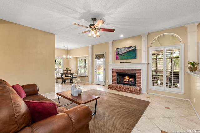 19502 Encino Bow, San Antonio, TX 78259 - living room featuring ceiling fan, light tile patterned flooring, ornate columns, a textured ceiling, and a fireplace
