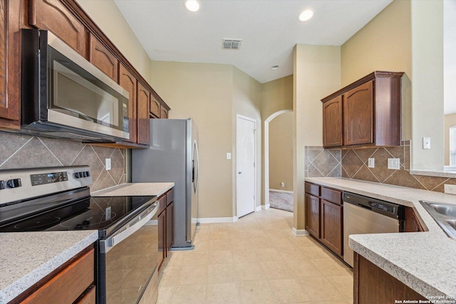 7738 Brisbane Bnd, Converse, TX 78109 - kitchen with stainless steel appliances, arched walkways, light countertops, decorative backsplash, and recessed lighting