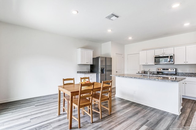 5323 Flying Hooves, San Antonio, TX 78222 - kitchen featuring appliances with stainless steel finishes, light wood-type flooring, a kitchen island with sink, white cabinets, and recessed lighting