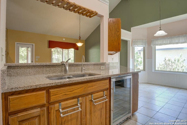 201 Cibolo Xing, Boerne, TX 78006 - kitchen with wine cooler, light stone countertops, brown cabinetry, a wainscoted wall, and pendant lighting