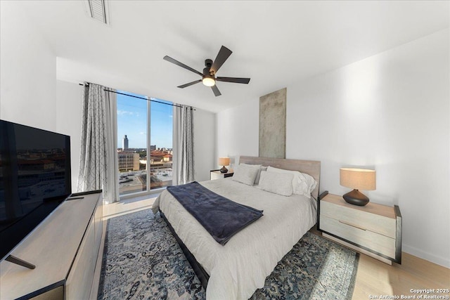 313 17th Unit, Austin, TX 78701 - bedroom with wood finished floors, a ceiling fan, access to outside, and a wall of windows