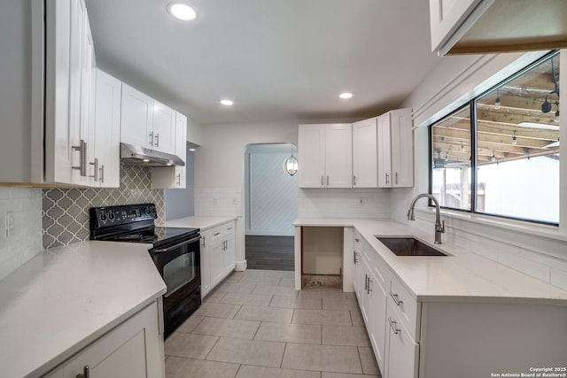 7711 Chatsworth, San Antonio, TX 78250 - kitchen with black range with electric stovetop, under cabinet range hood, white cabinets, light tile patterned flooring, and tasteful backsplash