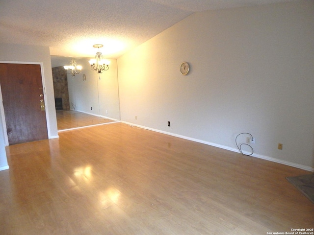 4119 Medical Unit 304F, San Antonio, TX 78229 - empty room featuring a chandelier, a fireplace, wood finished floors, lofted ceiling, and a textured ceiling