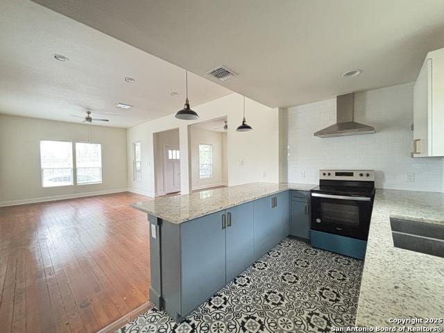 1014 Montana, San Antonio, TX 78203 - kitchen with wall chimney exhaust hood, stainless steel electric stove, ceiling fan, a peninsula, and light stone countertops