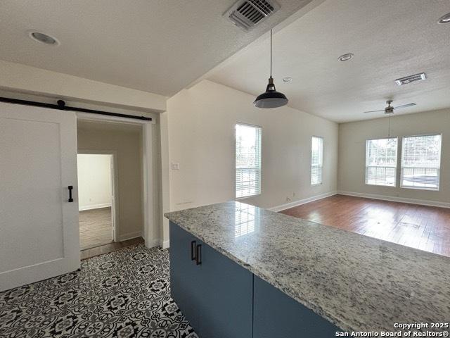 1014 Montana, San Antonio, TX 78203 - kitchen with a ceiling fan, a barn door, pendant lighting, recessed lighting, and light stone countertops