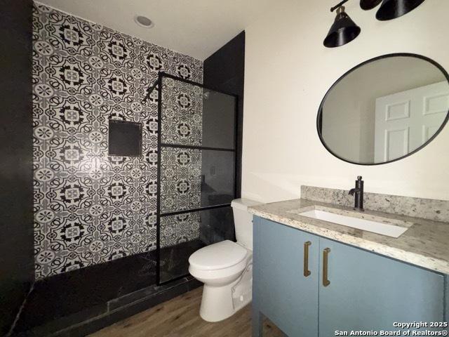 1014 Montana, San Antonio, TX 78203 - full bathroom featuring wood finished floors, vanity, and a tile shower
