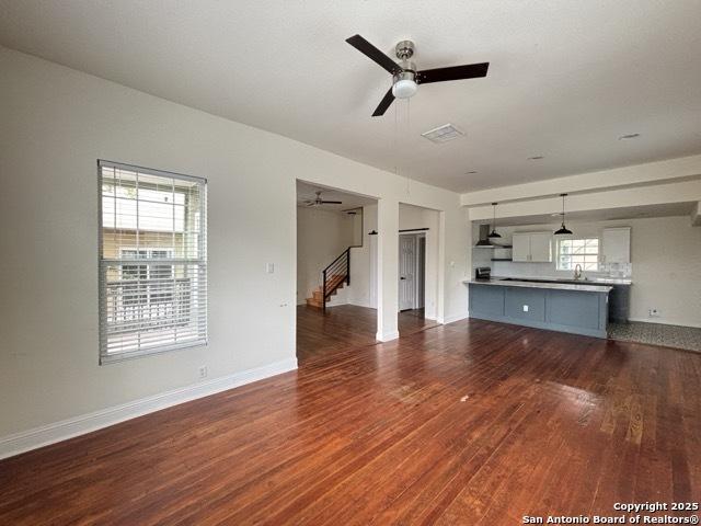 1014 Montana, San Antonio, TX 78203 - unfurnished living room with a ceiling fan, dark wood-type flooring, stairway, and plenty of natural light