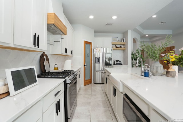 2863 Tortuga Verde, San Antonio, TX 78245 - kitchen with stainless steel appliances, custom range hood, decorative backsplash, open shelves, and white cabinetry