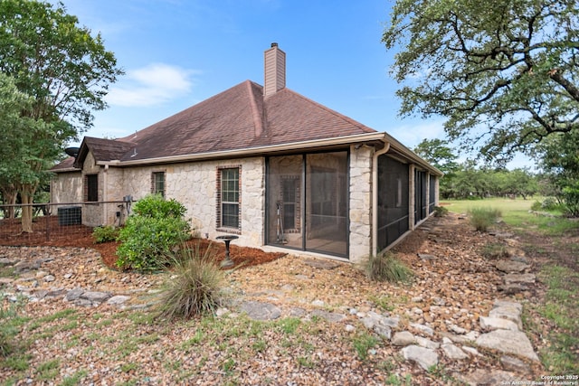 106 Oak Meadow Ln, Boerne, TX 78006 - back of property with stone siding, a chimney, a sunroom, and roof with shingles