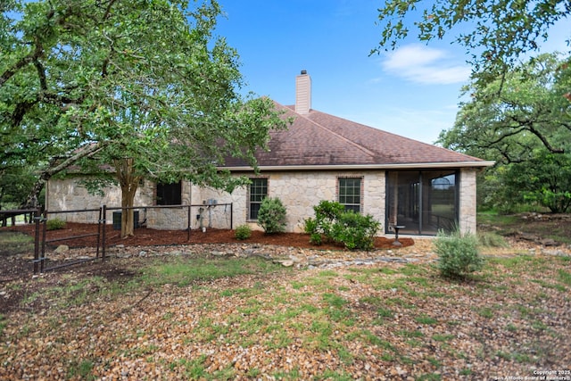 106 Oak Meadow Ln, Boerne, TX 78006 - rear view of property with stone siding, a chimney, a gate, a sunroom, and a shingled roof
