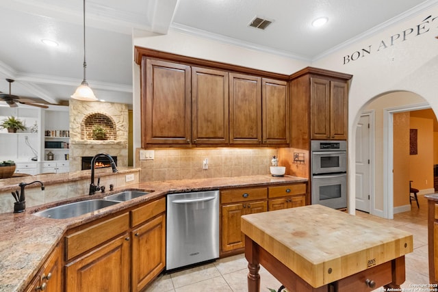 106 Oak Meadow Ln, Boerne, TX 78006 - kitchen featuring appliances with stainless steel finishes, light tile patterned floors, a stone fireplace, light stone counters, and ornamental molding