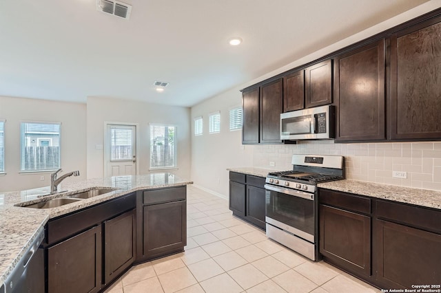 8904 Portobello Way, Converse, TX 78109 - kitchen with appliances with stainless steel finishes, dark brown cabinetry, light tile patterned floors, decorative backsplash, and recessed lighting