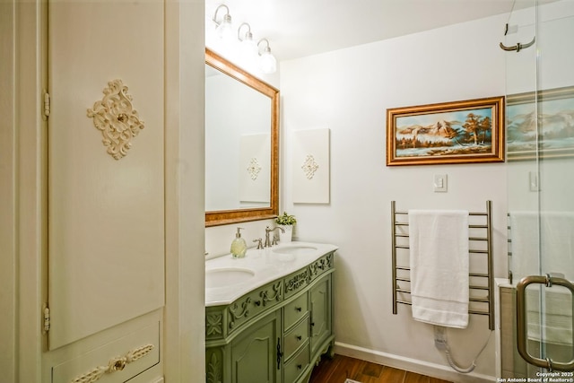505 Winfield Blvd, Windcrest, TX 78239 - full bathroom featuring a towel warmer, double vanity, wood finished floors, and a shower with shower door