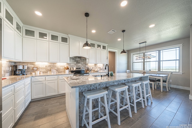 919 Pinto Cyn, Bandera, TX 78003 - kitchen featuring stainless steel range with electric stovetop, backsplash, a kitchen island with sink, white cabinets, and recessed lighting