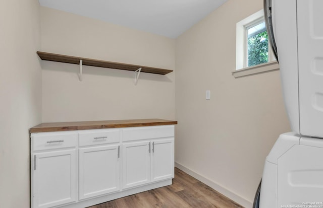11115 Rendezvous, San Antonio, TX 78216 - laundry area with stacked washer / dryer, light wood-style flooring, and cabinet space