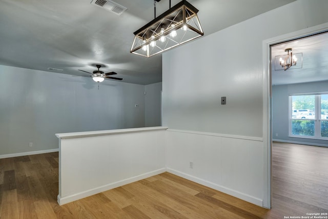 8302 Hastings, San Antonio, TX 78239 - spare room featuring a chandelier, wood finished floors, a wainscoted wall, and a ceiling fan