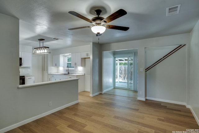 8302 Hastings, San Antonio, TX 78239 - kitchen featuring white cabinets, a ceiling fan, light wood-style floors, a peninsula, and light countertops
