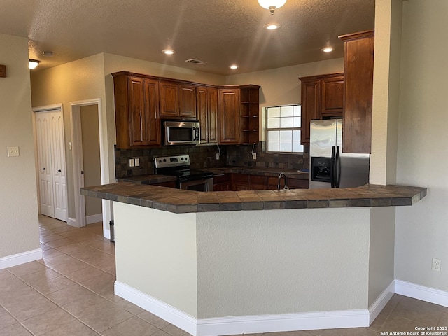 812 33rd St, Hondo, TX 78861 - kitchen with stainless steel appliances, a peninsula, decorative backsplash, open shelves, and a textured ceiling