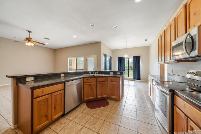 312 Bunker Hl, Pleasanton, TX 78064 - kitchen with appliances with stainless steel finishes, dark countertops, light tile patterned flooring, brown cabinets, and recessed lighting