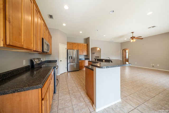 312 Bunker Hl, Pleasanton, TX 78064 - kitchen with stainless steel appliances, arched walkways, light tile patterned flooring, a ceiling fan, and a kitchen island with sink