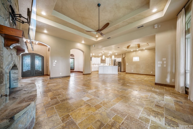 1437 Decanter, New Braunfels, TX 78132 - unfurnished living room with a tray ceiling, arched walkways, stone tile flooring, recessed lighting, and a high ceiling
