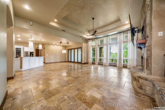 1437 Decanter, New Braunfels, TX 78132 - unfurnished living room with stone tile floors, a raised ceiling, and recessed lighting