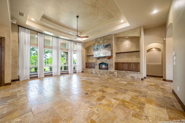 1437 Decanter, New Braunfels, TX 78132 - unfurnished living room featuring stone tile floors, built in features, a tray ceiling, arched walkways, and a high ceiling