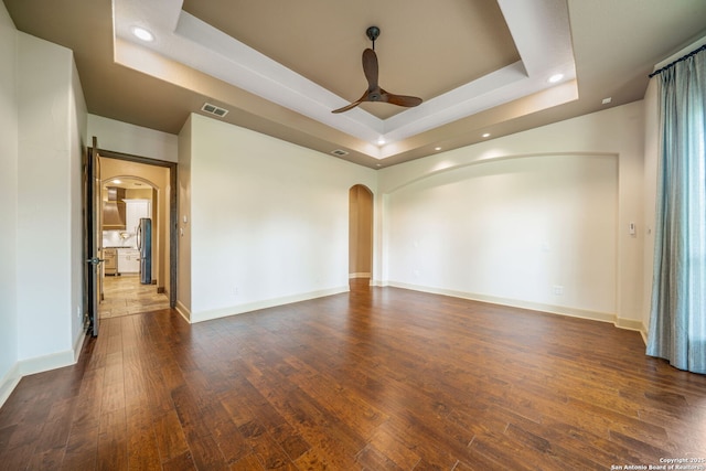 1437 Decanter, New Braunfels, TX 78132 - spare room with arched walkways, a tray ceiling, ceiling fan, recessed lighting, and dark wood-style floors