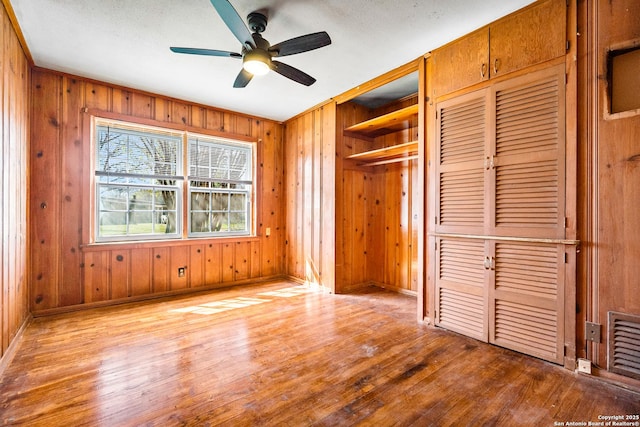 231 Craigmont, San Antonio, TX 78213 - unfurnished bedroom with wood finished floors, wood walls, and a ceiling fan