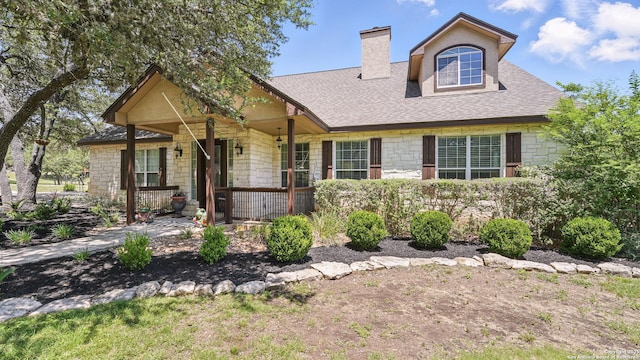212 Wentworth, Spring Branch, TX 78070 - view of front of house with stone siding, a chimney, covered porch, and roof with shingles