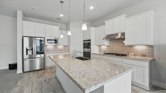 1606 Folk Victorian, New Braunfels, TX 78132 - kitchen featuring stainless steel appliances, under cabinet range hood, white cabinets, a center island with sink, and decorative backsplash