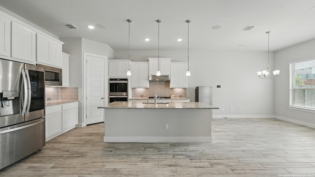 1606 Folk Victorian, New Braunfels, TX 78132 - kitchen with appliances with stainless steel finishes, under cabinet range hood, tasteful backsplash, recessed lighting, and an island with sink