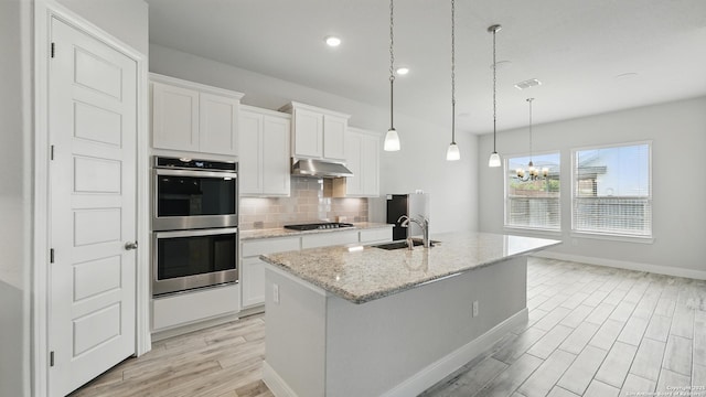 1606 Folk Victorian, New Braunfels, TX 78132 - kitchen with double oven, black gas stovetop, light wood-type flooring, under cabinet range hood, and tasteful backsplash