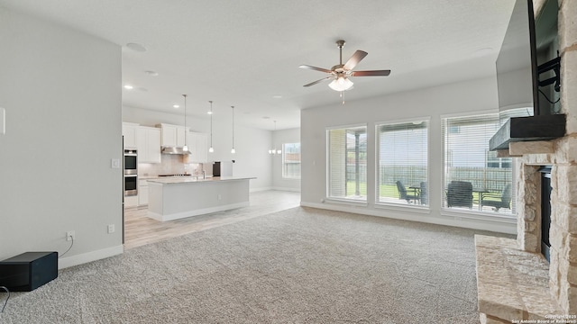 1606 Folk Victorian, New Braunfels, TX 78132 - unfurnished living room with light colored carpet, ceiling fan, a stone fireplace, and recessed lighting